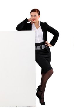 Attractive woman standing beside a blank sign clipart