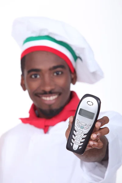 A black chef handing a phone. — Stock Photo, Image