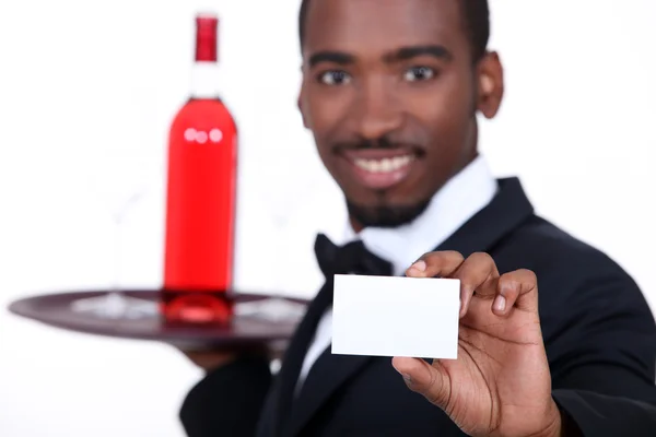 Camarero con una botella de vino rosa y una tarjeta de visita en blanco — Foto de Stock