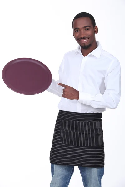 Mladý černý číšník ukazující jeho talíř — Stock fotografie