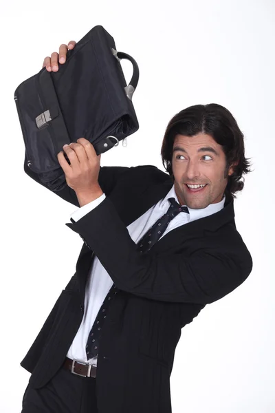 A business man is protecting his face with a briefcase, he looks amused — Stock Photo, Image