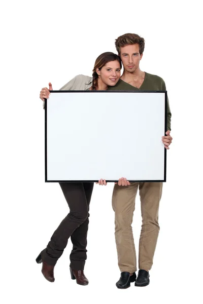 Trendy giovane coppia in piedi con cornice vuota — Foto Stock