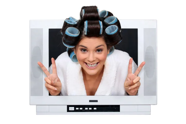 Женщина с бигуди, заглядывающая в телевизор — стоковое фото