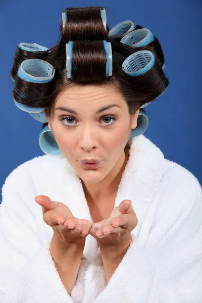 Woman with her hair in rollers blowing a kiss — Stock Photo, Image