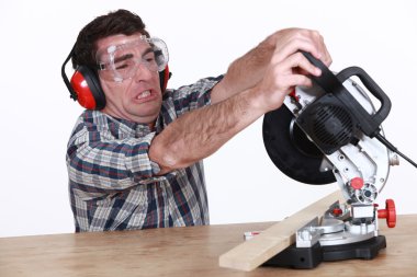 Man struggling to use a mitre saw clipart