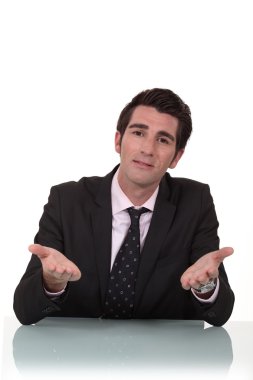 Businessman sitting at a desk talking to you clipart