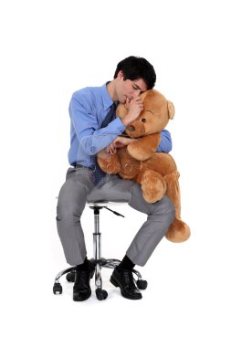 An adult businessman hugging a big teddy bear. clipart