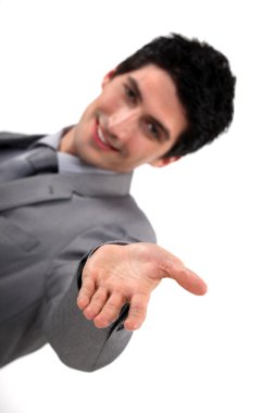 Young handsome businessman reaching out his hand clipart