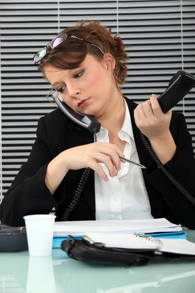 Sekreterare belastas med två telefoner — Stockfoto