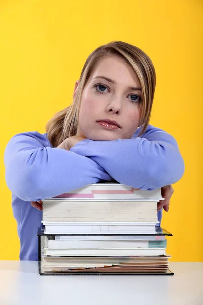 Estudante feminina apoiada em livros empilhados — Fotografia de Stock