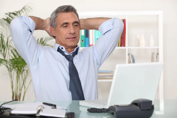 Affärsman stretching vid sitt skrivbord — Stockfoto