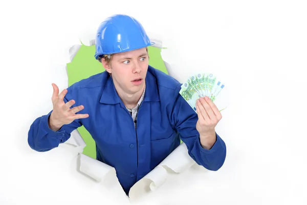 Craftsman holding bills and looking surprised — Stock Photo, Image