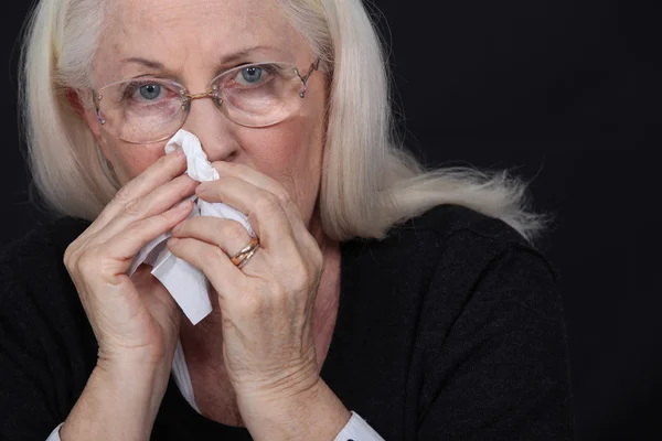 Oudere vrouw haar neus waait — Stockfoto