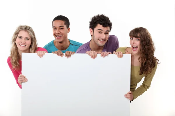 Grupo de amigos segurando um cartaz em branco — Fotografia de Stock