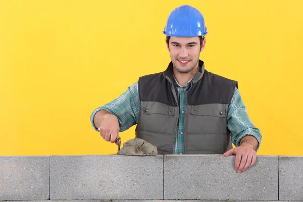 Мейсон разбрасывает цемент на стену лопатой — стоковое фото