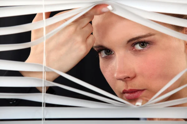 Mujer mirando a través de persianas —  Fotos de Stock