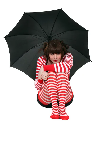 Woman holding an umbrella and dressed in clothing with a red stripe pattern — Stock Photo, Image