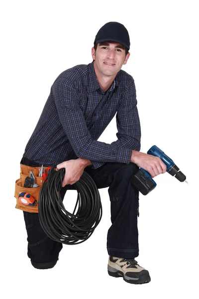 Handyman med borrmaskin knästående — Stockfoto