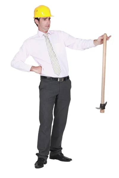 Architect sheepishly holding pick-axe — Stock Photo, Image