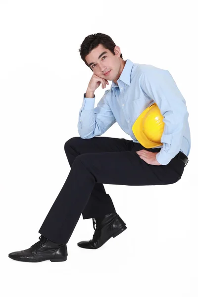 Young engineer sitting on an invisible stool — Stock Photo, Image