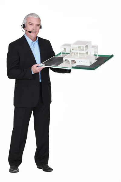 Architect wearing head-set and holding model housing — Stock Photo, Image