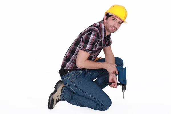Man with power drill kneeling — Stock Photo, Image
