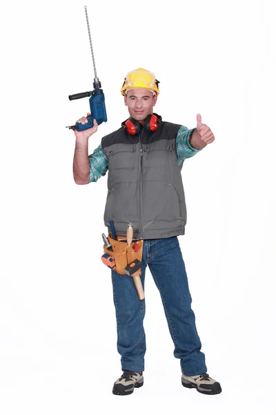 A handyman with a drill giving the thumb up. — Stock Photo, Image