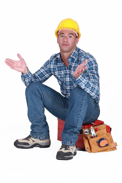 Craftsman sitting on his toolbox and gesturing — Stock Photo, Image