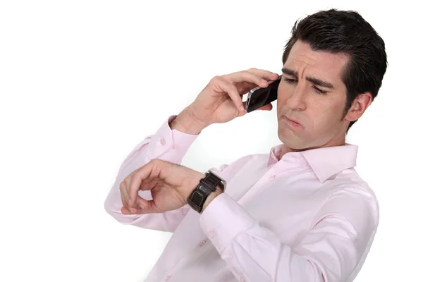 Un hombre de negocios por teléfono mirando su reloj . — Foto de Stock