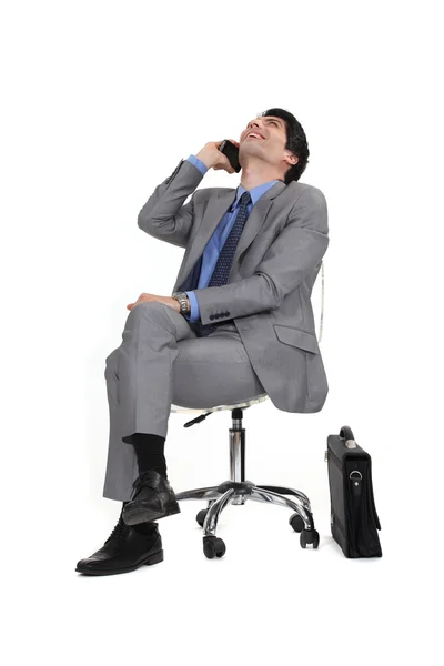Telefonla bir sandalyede oturan adam — Stok fotoğraf