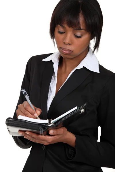 Fed-up businesswoman writing in her agenda — Stock Photo, Image