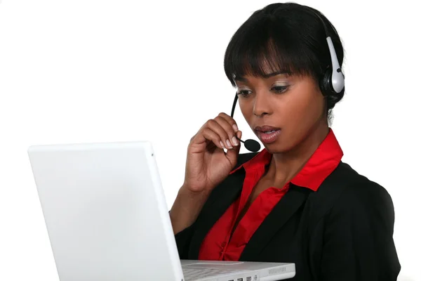 Mulher de negócios usando um fone de ouvido com um laptop — Fotografia de Stock