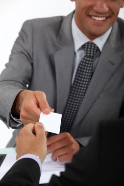 Businessman handing over his business card to a potential client clipart