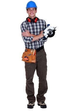 Portrait of a young tradesman holding a circular saw clipart