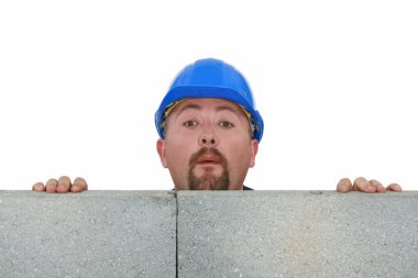 Builder peering over wall clipart