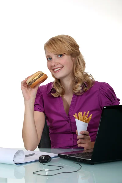 Γυναίκα που τρώνε χάμπουργκερ στο γραφείο — Φωτογραφία Αρχείου