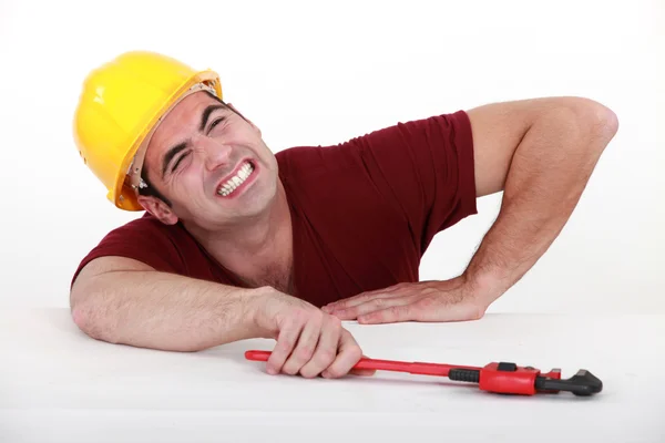 Workman with a wrench in a tight spot — Stock Photo, Image