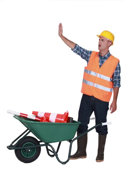 Builder making stop gesture while stood with traffic cones — стоковое фото