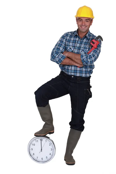 Tradesman com o pé apoiado em um relógio — Fotografia de Stock