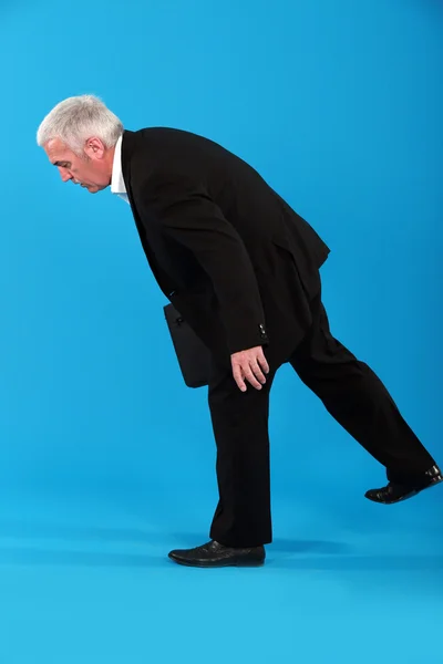 Alter Geschäftsmann kämpft darum, auf den Beinen zu bleiben — Stockfoto
