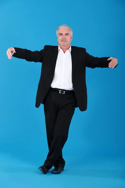 Businessman dancing alone on blue background — Stock Photo, Image