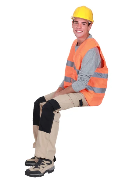 Young tradesman sitting on an invisible block — Stock Photo, Image