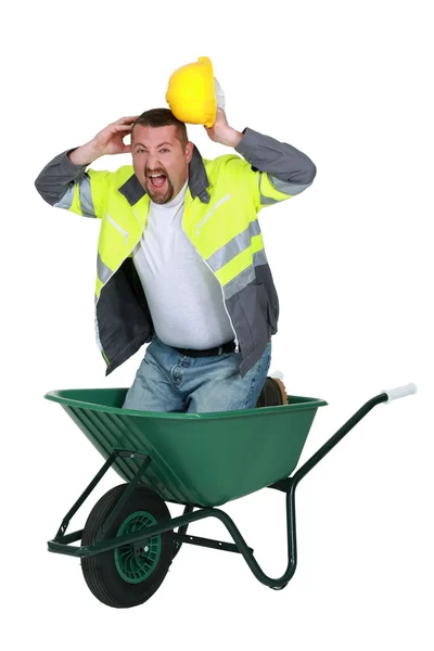 Construtor gritando enquanto ajoelhado no carrinho de mão — Fotografia de Stock