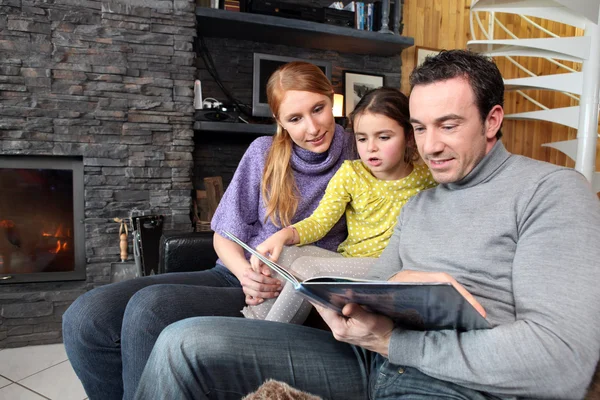 Pais felizes lendo sua filha uma história — Fotografia de Stock