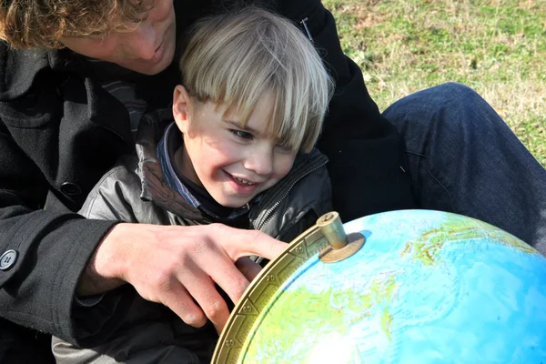 Vader en zoon kijken naar een globe — Stockfoto