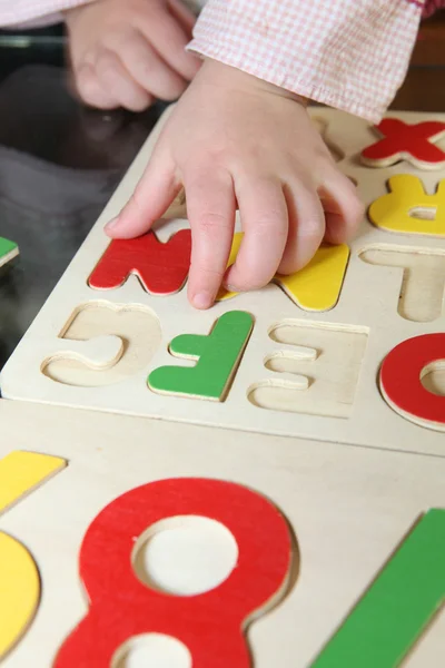 Маленький ребенок играет с буквами головоломки — стоковое фото
