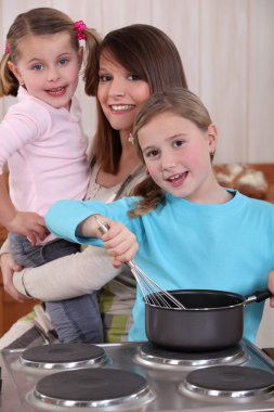 Mother and two young daughters cooking clipart