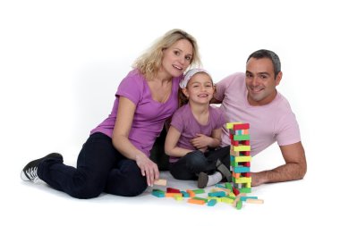 Parents watching their daughter play with blocks clipart