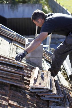 Roofer repairing a badly damaged roof clipart