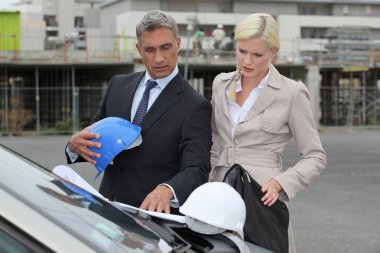 Male and female architects stood by car clipart